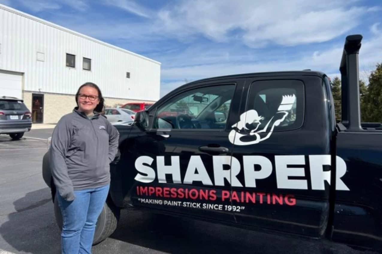 female worker of sharper impressions painting posing beside a company truck