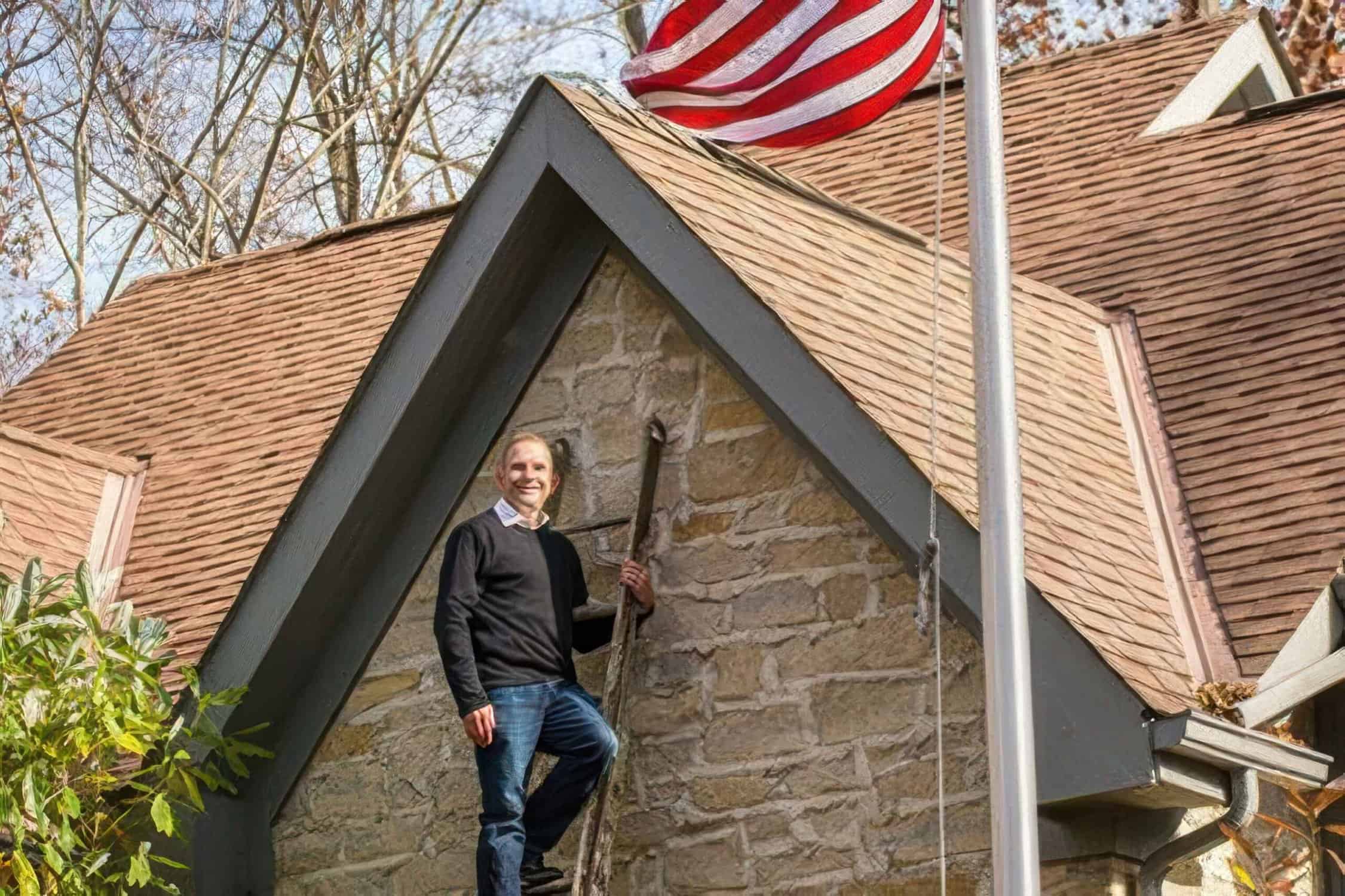 man standing on top of a ladder placed along a house