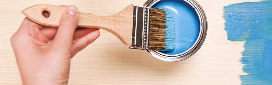 a painter dipping the paint brush into the blue paint